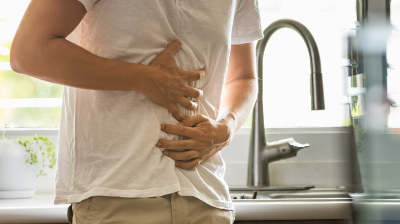 Man holding stomach standing in front of sink