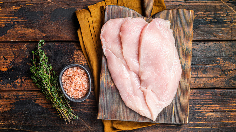 Thinly sliced chicken breast on wooden cutting board