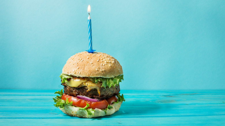 A fast food hamburger with a birthday candle in it