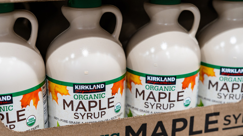 Four jugs of Kirkland Signature maple syrup on shelf at Costco