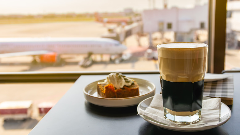 Coffee and pastry on a table with plane outside