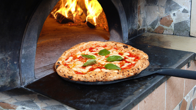 Cooked pizza coming out of a pizza oven