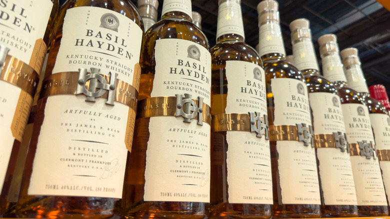 A low angle shot of a row of Basil Hayden bottles on a liquor shelf