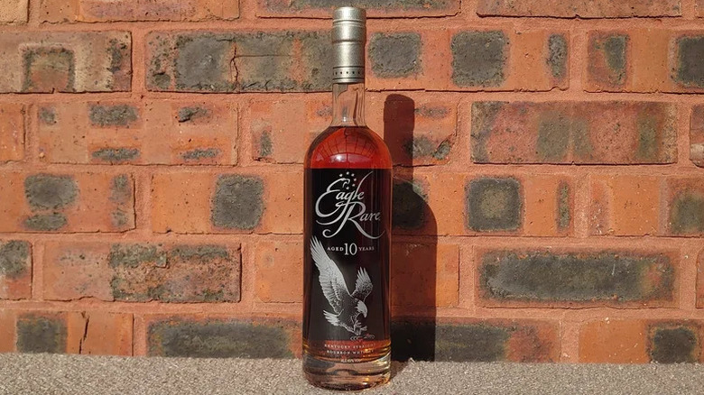 A bottle of Eagle Rare 10-year posed in sunlight in front of a brick background
