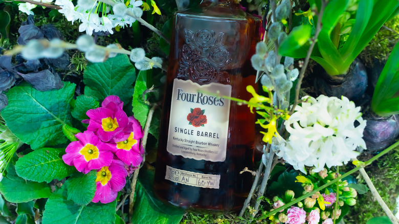 A bottle of Four Roses Single Barrel laid down and surrounded by a variety of flowers