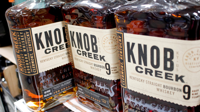 A close shot of three bottles of Knob Creek 9-year on a liquor shelf with one facing sidewards
