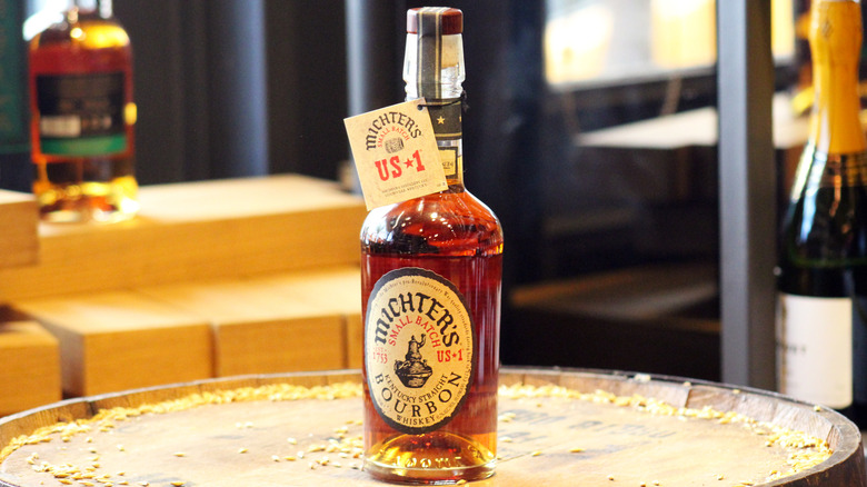 A bottle of Michter's US*1 posed on top of a barrel with grain scattered around
