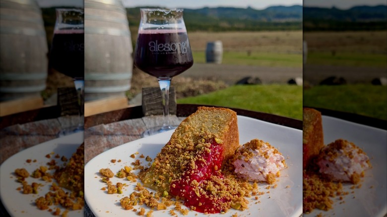 Glass of beer with a plate of cake and blurred countryside in the background