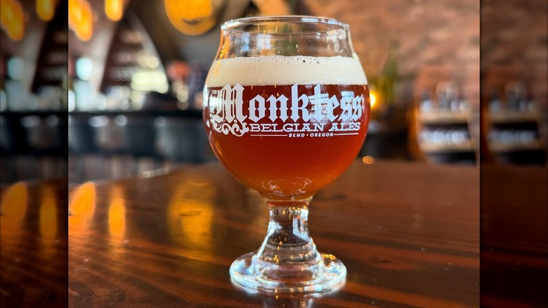 Glass of Belgian beer on wooden table with blurred brick background
