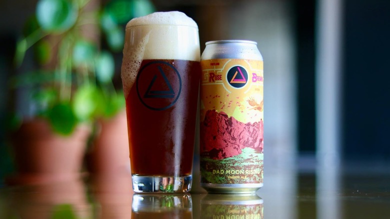 Can and glass of beer on shiny table with blurred background