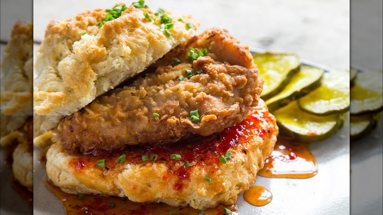 Chicken biscuit with hot honey and pickles on the side