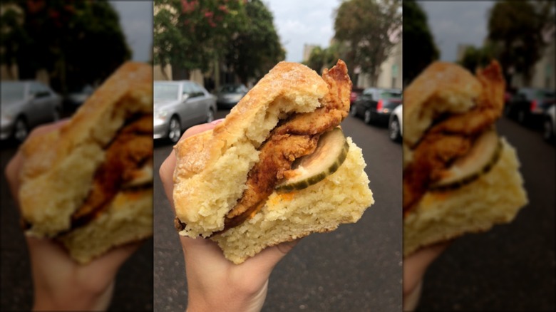 Hand holding chicken biscuit with pickles