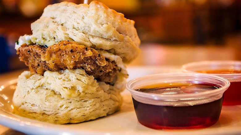 Chicken biscuits on white plate with cups of honey