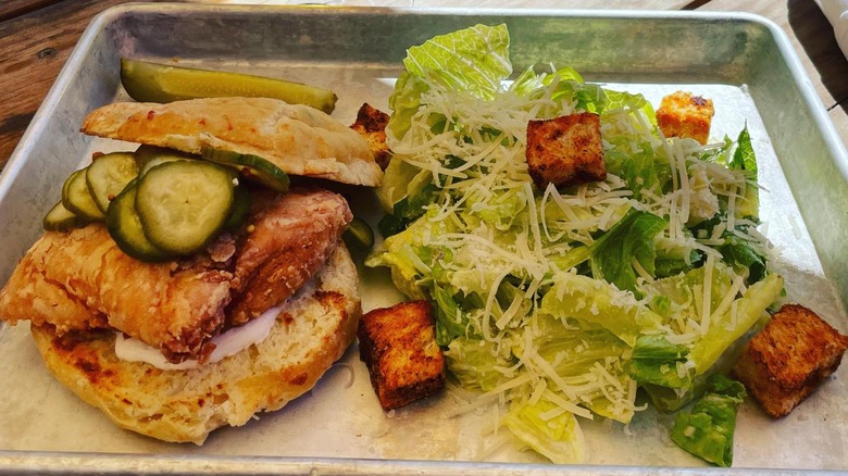 Fried chicken biscuit with pickles and salad on the side