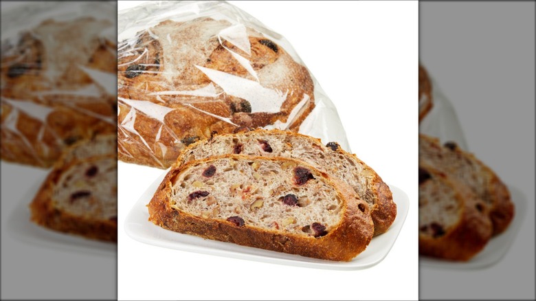 Costco Kirkland Signature cranberry walnut round bread in plastic bag with a couple of slices on a white plate.