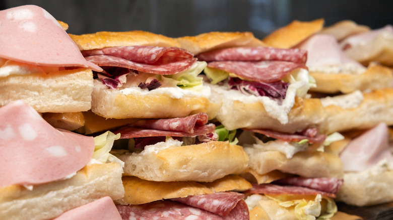 Stacks of Italian deli sandwiches containing meat, lettuce, and cheese