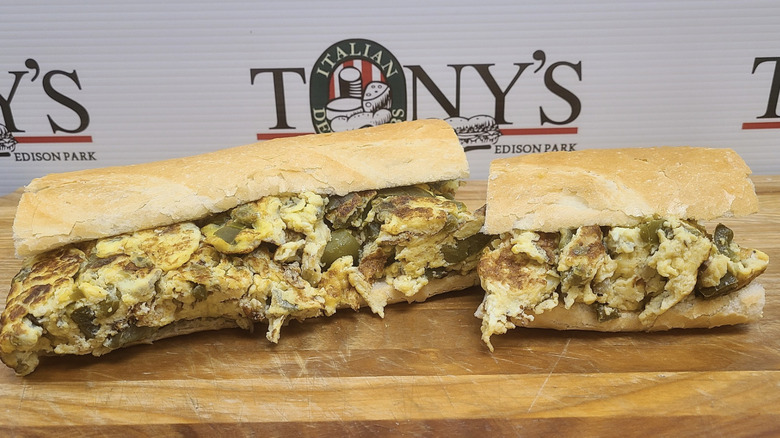 Stuffed meat and cheese sub cut in half in front of a sign for Tony's Italian Deli & Subs