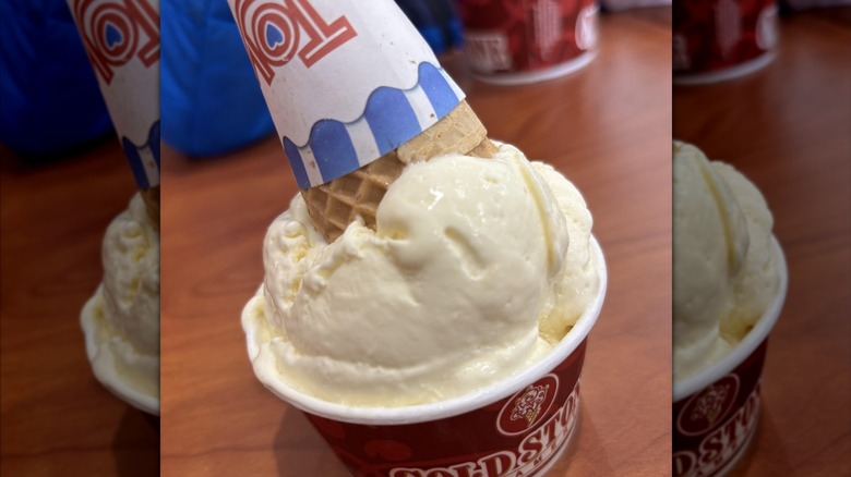 A cup of Cold Stone Creamery Lemon Cake Batter ice cream with an ice cream cone upturned on top