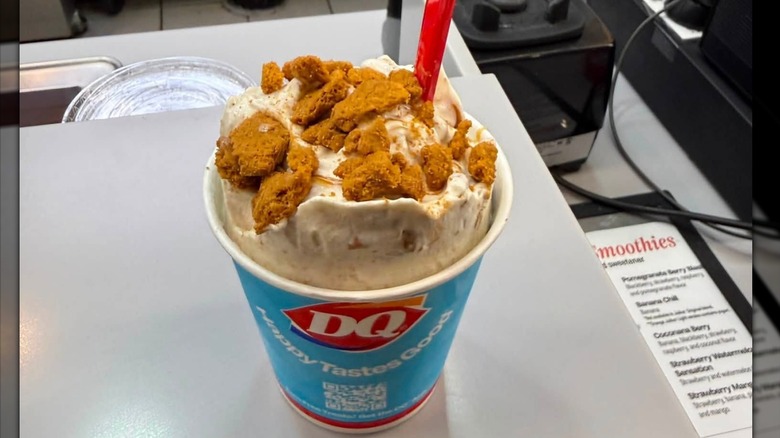 A Biscoff Blizzard in a Dairy Queen cup with a red straw and crumbled cookie on top