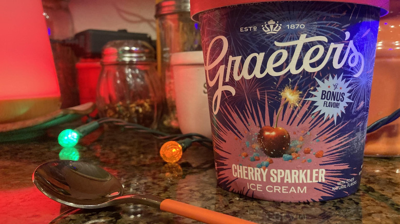 A pint of Garaeter's Cherry Sparkler ice cream on a kitchen counter with some patio lights