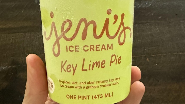 Ahand holding a pint of Jeni's Key Lime Pie Ice Cream