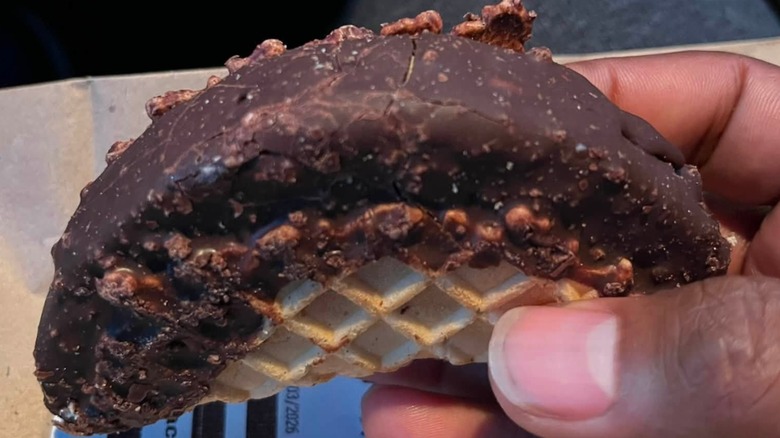 Fingers holding a chocolate-dipped waffle cone taco