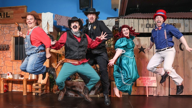 Group of performers in Western gear jumping above the stage