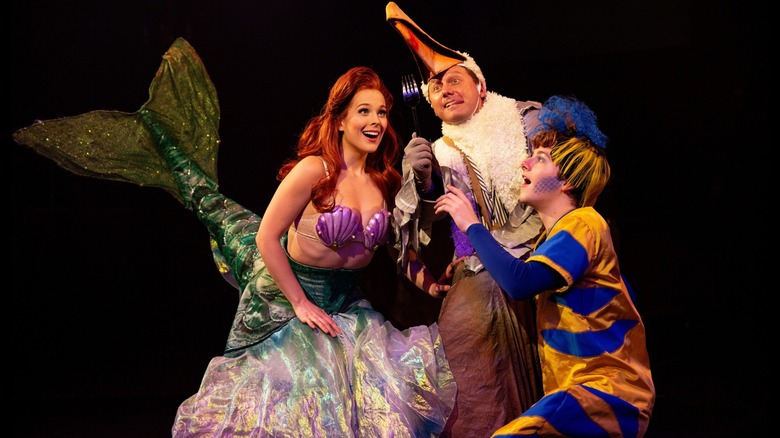 Three people on stage in performance of The Little Mermaid