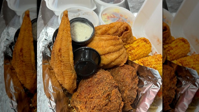 Fried catfish with pork chops, corn, and sies in takeout container