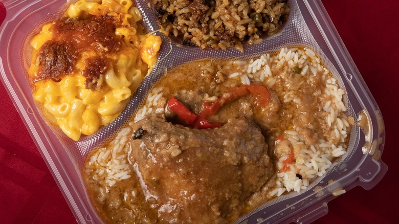 Smothered pork chops with rice and mac and cheese in takeout container