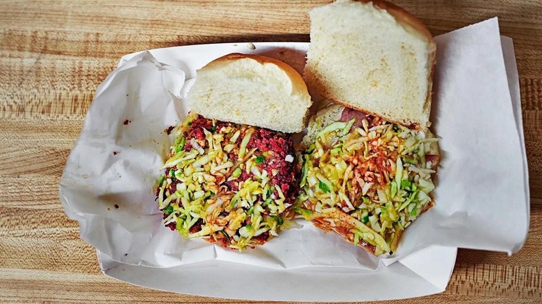 Sandiwch open on wood-grain background and paper