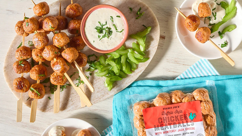 Trader Joe's Buffalo Style Chicken Meatballs on skewers next to cups of dipping sauce and sliced celery