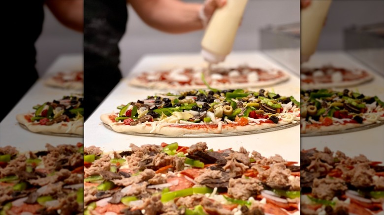 Three Brenz pizzas with meats and veggies on a white countertop