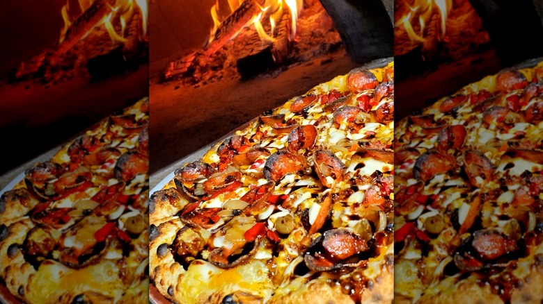 Close-up on a butternut squash sauce pizza in front of a wood-fired oven