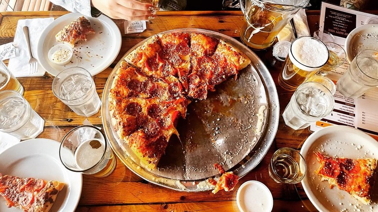 Table filled with Hounddogs Pizza slices and beer