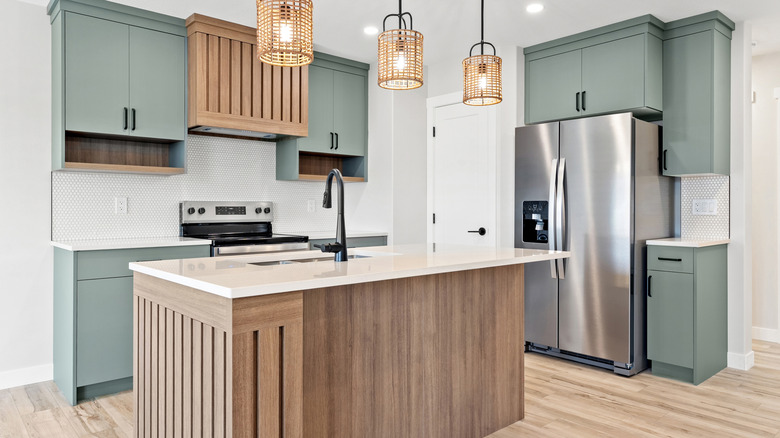 Kitchen with a stainless steel refrigerator and a wooden island. The kitchen is clean and well-lit