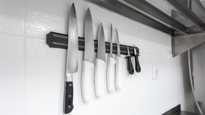 Sharp knives are organized neatly on a magnetic strip in a bright kitchen setting