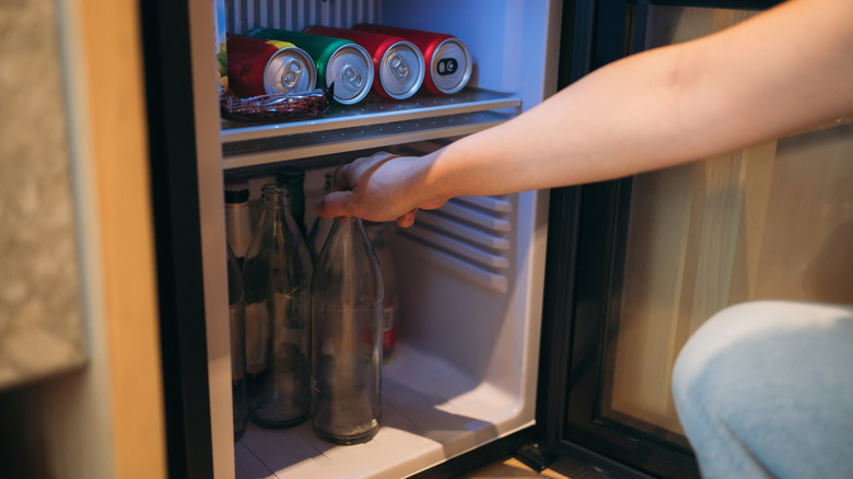 Close-up of a Hand Grabbing a Bottle from a Mini Fridge