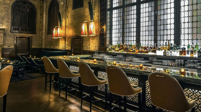 A bar with bar stools and large windows.