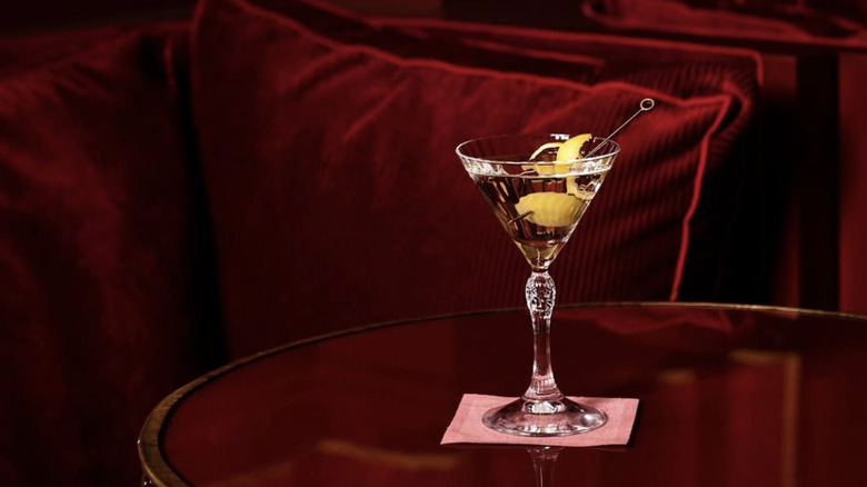 a martini with a twist on a red table with red cushions in the background.