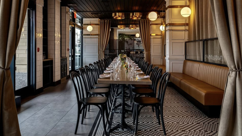 A large table framed by beige curtains and brown leather banquettes