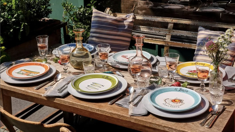 A wooden table with colorful plates and flower vases on top