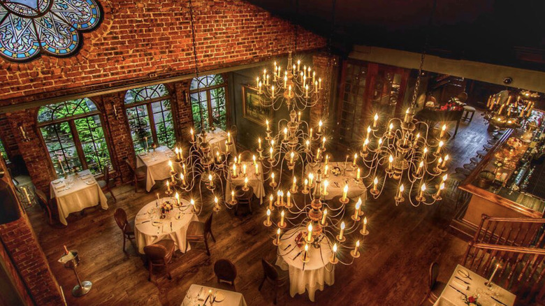 Candlelit dining room with chandeliers and exposed brick walls