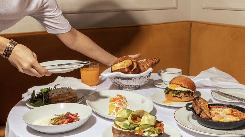 Man setting down a plate on a white clothed table covered with various dishes