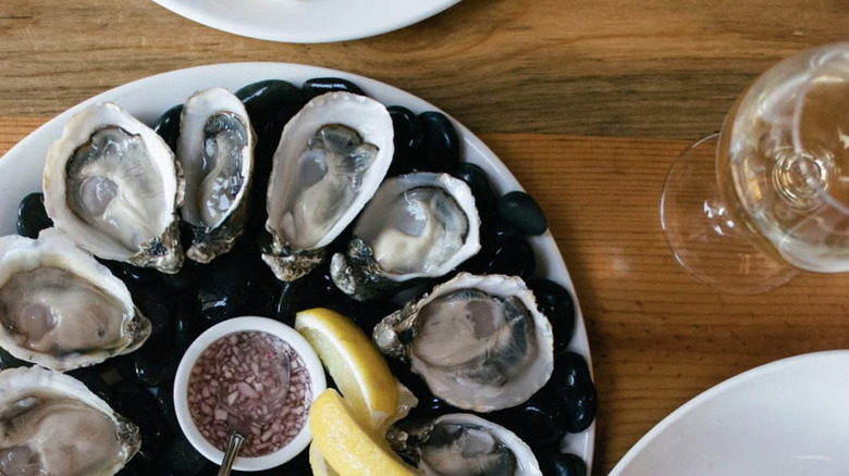 Platter of raw oysters with sauce in the middle