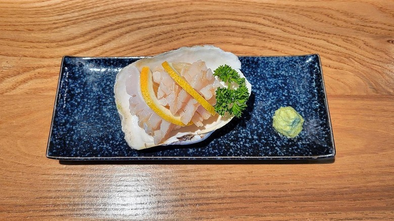 Geoduck crudo on oyster shell on wooden table