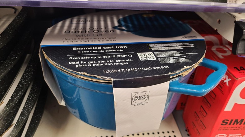 Blue enameled cast iron Dutch oven with lid on a shelf.