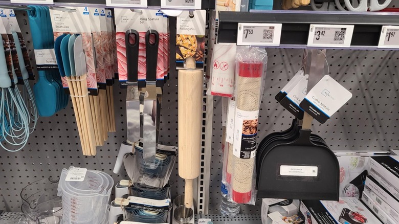 Rolling pin surrounded by other baking tools hanging on a rack.