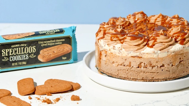 Speculoos cookies on table alongside sleeve of cookies and multi-layered cheesecake starring cookies