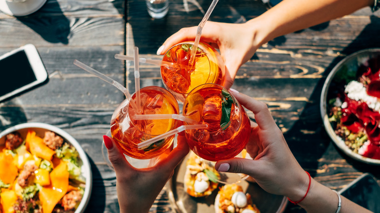people toasting with aperol spritzes